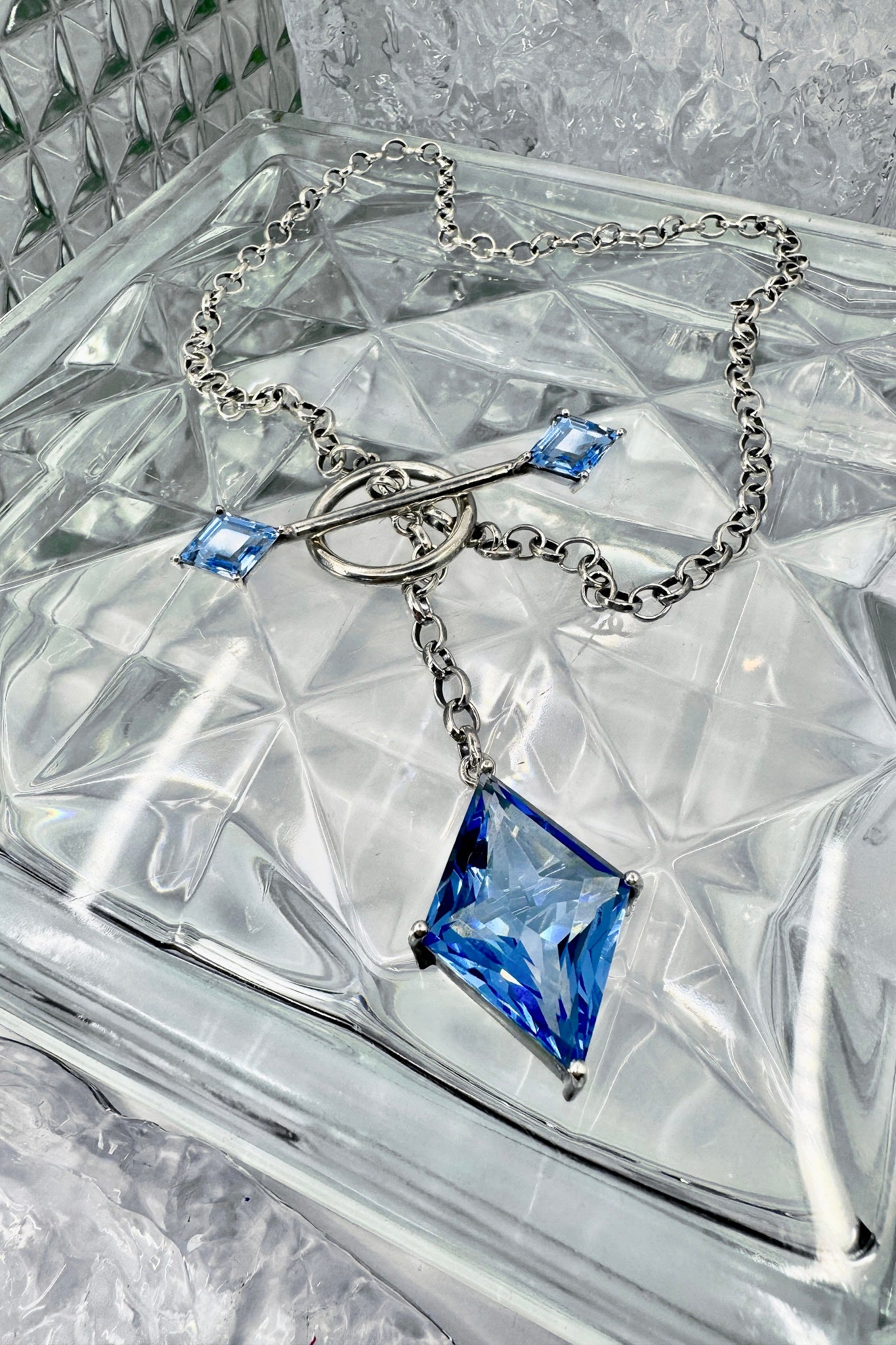 Silver necklace with blue gemstones on a textured surface