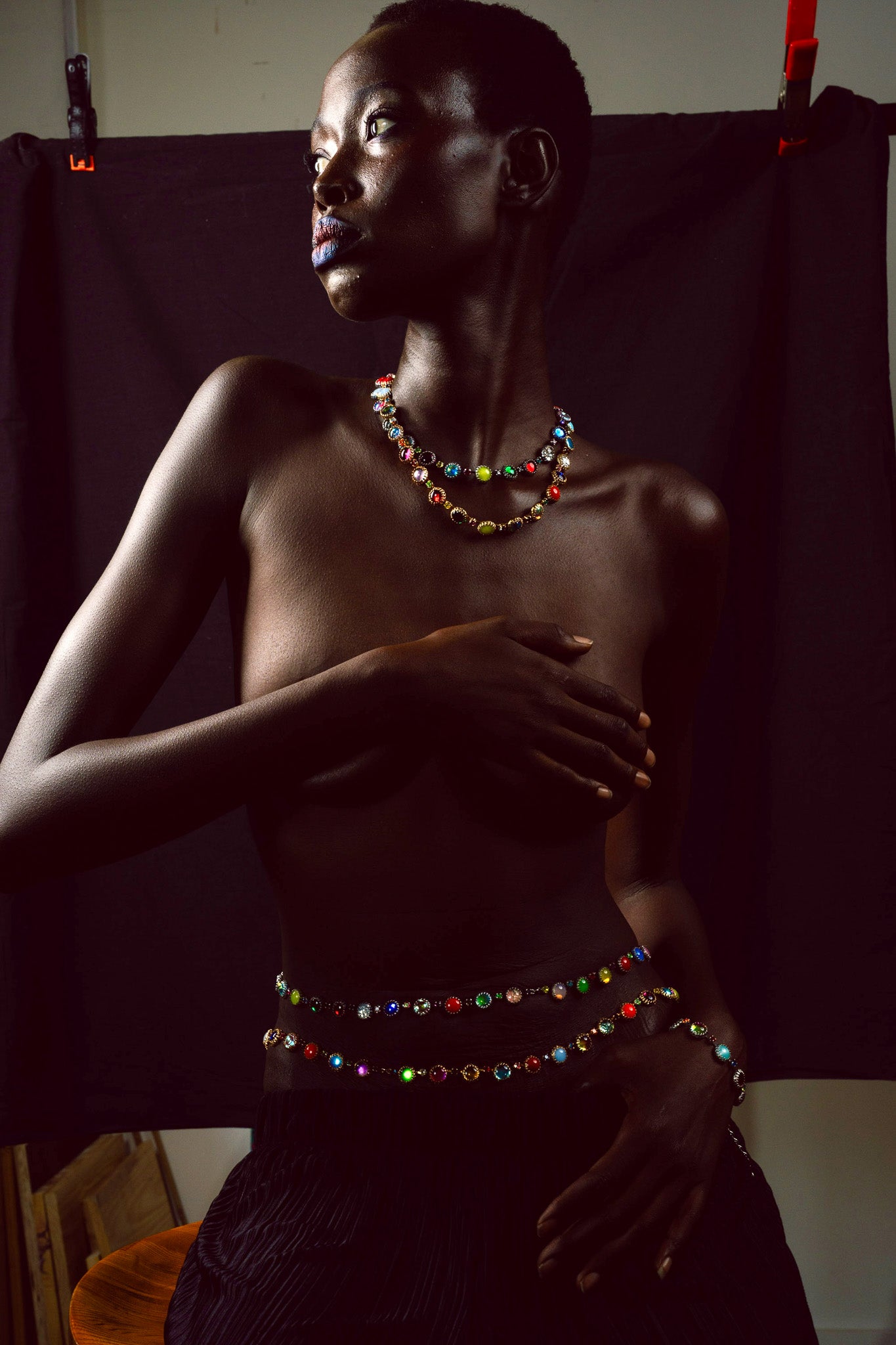 Model wearing colorful jewelry against a dark fabric backdrop