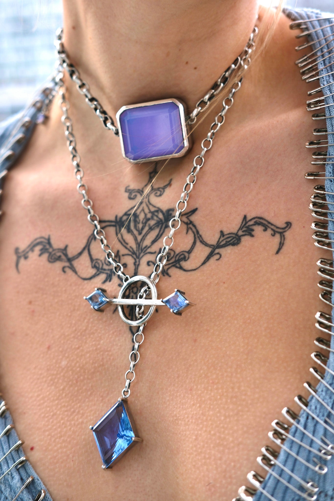 Necklace with blue gemstones on a person's neck with tattoos
