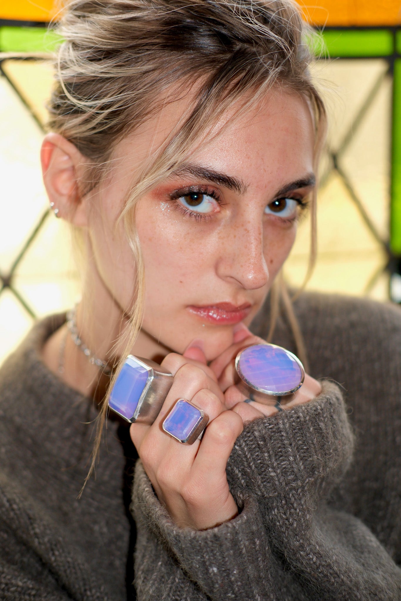 Woman wearing multiple rings with a stained glass window in the background