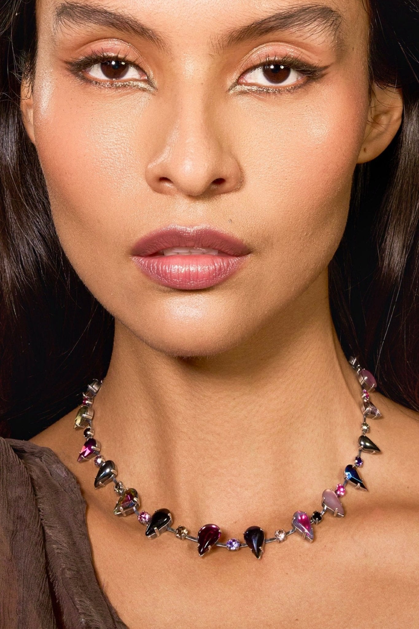 Close-up of a woman wearing a colorful gemstone necklace.