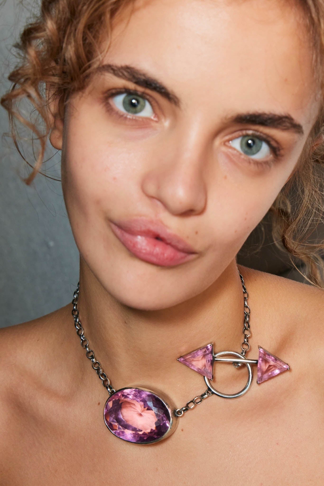 Close-up of a person wearing a sterling silver necklace with a pink colossus pendant