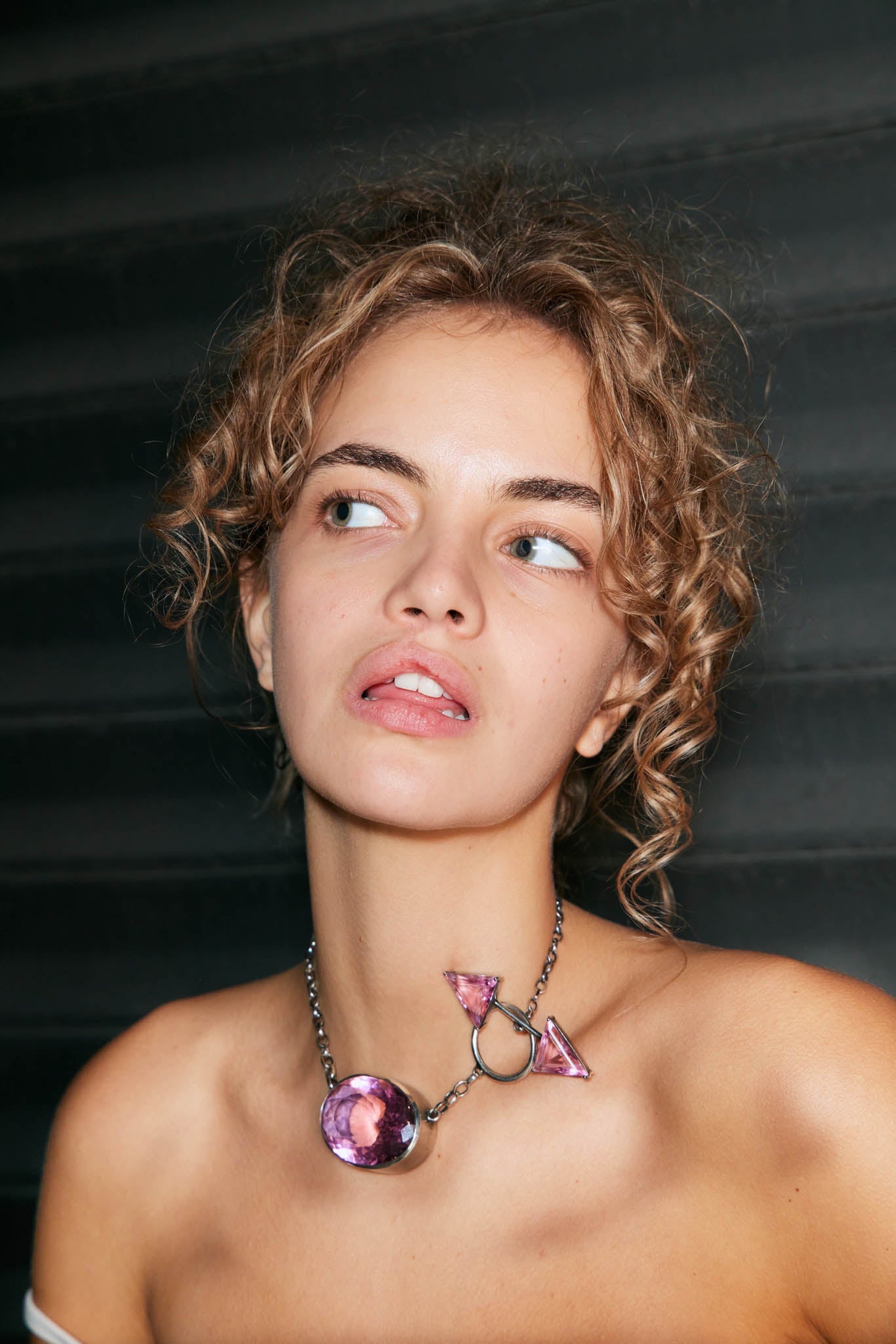 Woman wearing a sterling silver necklace with a colossus pink gemstone against a dark background