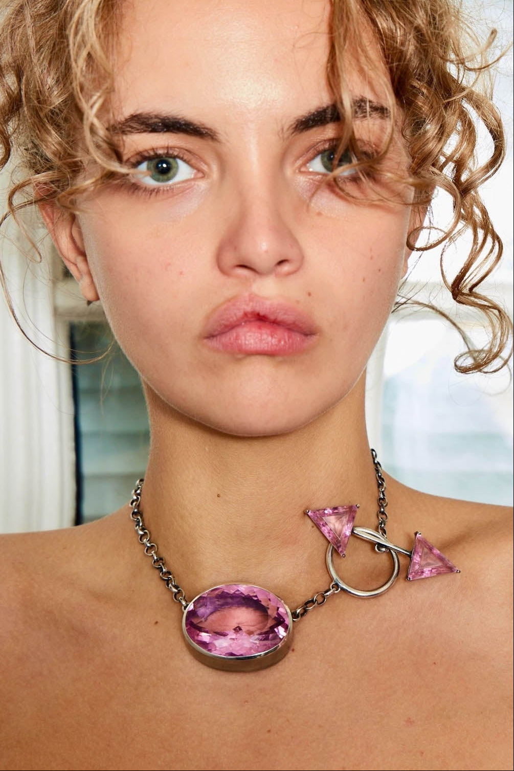 Woman wearing a pink sterling silver necklace with a large colossus pendant.