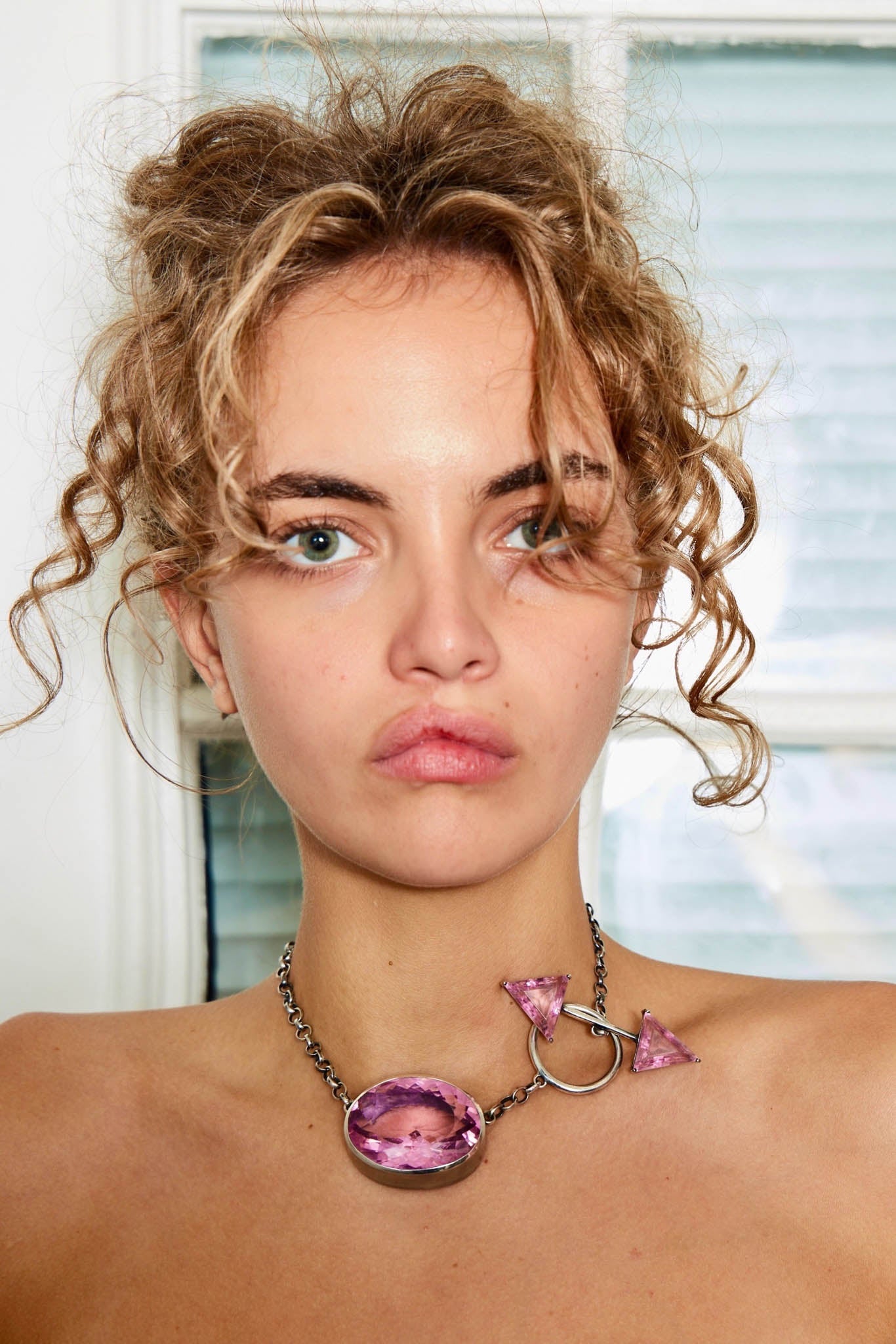 Woman wearing a pink sterling silver necklace with a large colossus pendant.