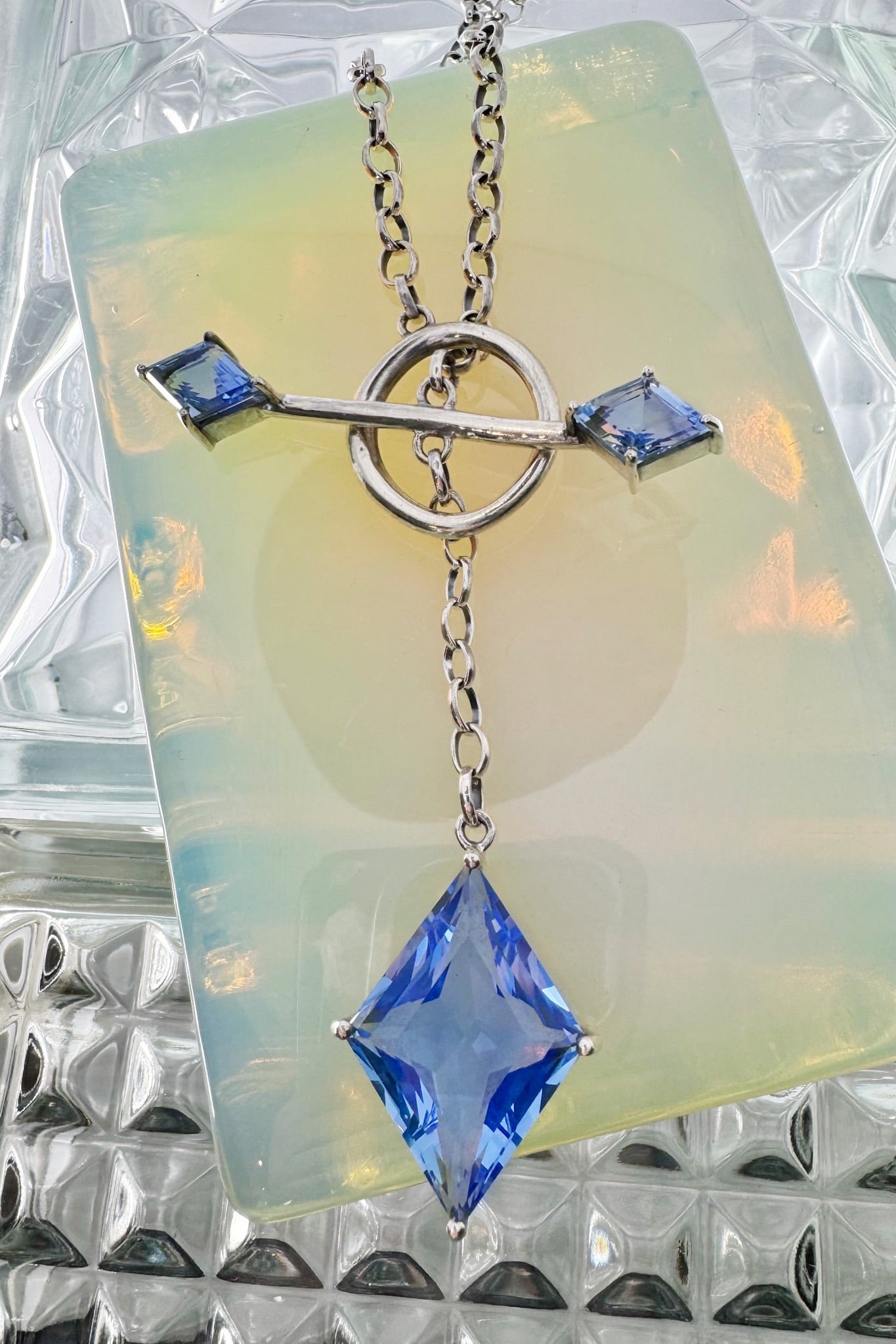 Silver necklace with blue gemstones on a opal background.