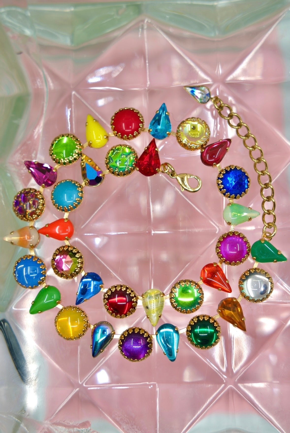 Colorful gemstone necklace on a pink and green geometric background