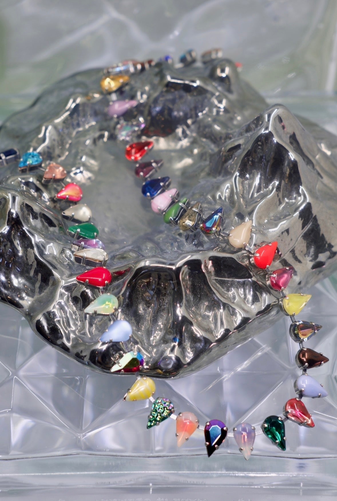 Colorful stone necklace resting on a metallic stone.