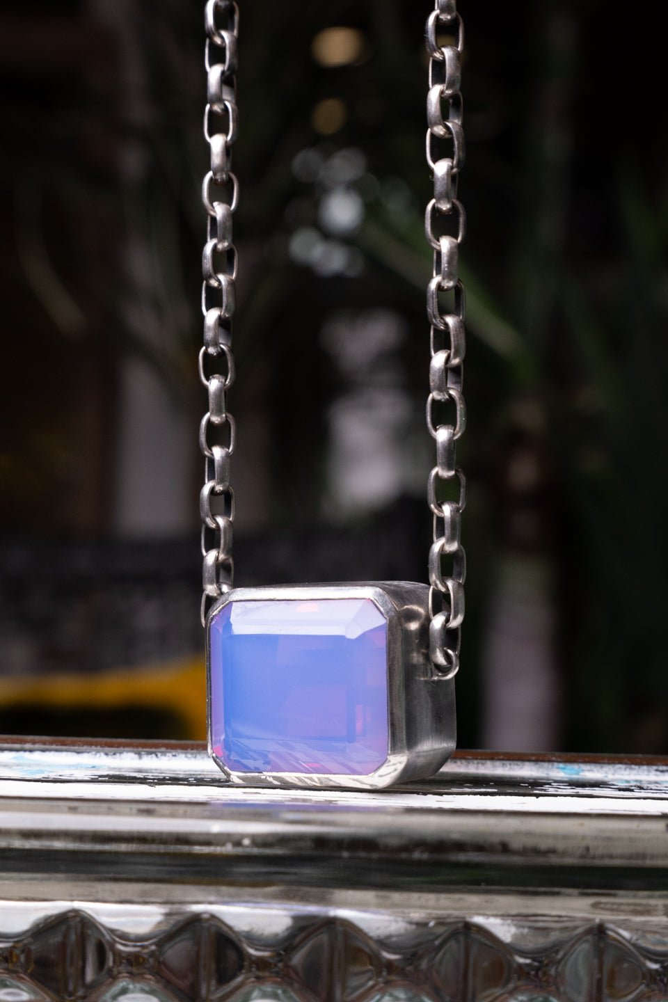 Necklace with a lavender pendant on a reflective surface
